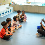 kids forming a circle hearing Putonghua Teacher read a story