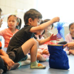 Boy getting scarf out during circle time with Putonghua teacher